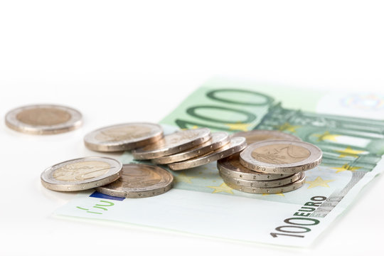 Close-up of a hundred euro banknote and euro coins on white background.