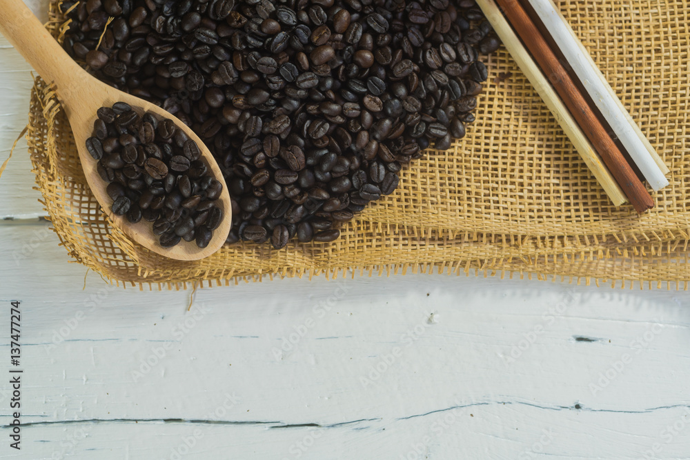 Wall mural Coffee beans on sack with white wood table.