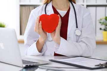 Unknown female doctor with stethoscope holding heart. Cardiology and medical care concept