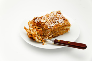 French Napoleon Cake of puff pastry with sour cream on a white plate close-up. Nutritious dessert. Selected Focus