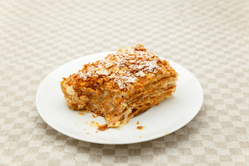 French Napoleon Cake of puff pastry with sour cream on a white plate close-up. Nutritious dessert. Selected Focus