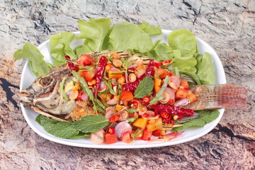 Spicy and sour fried Tilapia Salad with baby tamarind leaves .