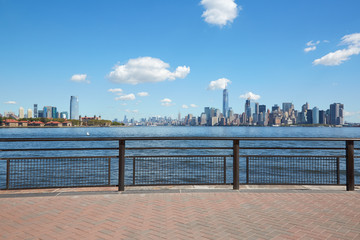 New York city skyline and Ellis Island view from empty dock terrace in a sunny day