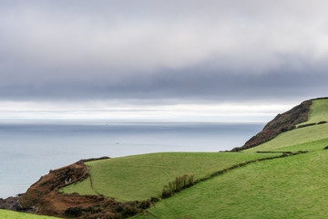 Rolling hills leading to an expanse of sea, under overcast sky