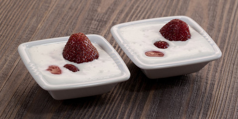Strawberry with whipped cream in a bowl on a wooden table