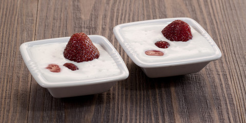 Strawberry with whipped cream in a bowl on a wooden table