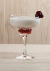 Strawberry with whipped cream in a glass on a wooden table