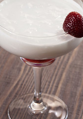 Strawberry with whipped cream in a glass on a wooden table