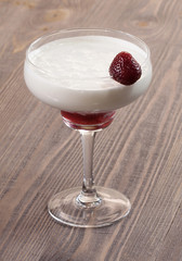 Strawberry with whipped cream in a glass on a wooden table