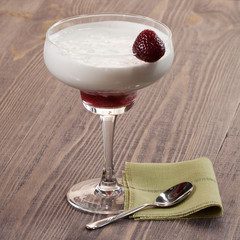 Strawberry with whipped cream in a glass on a wooden table