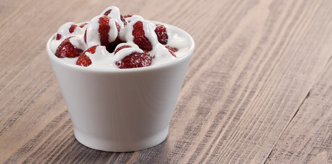 Strawberry with ice cream in a dish on a wooden table