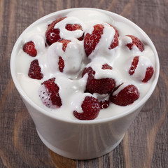 Strawberry with ice cream in a dish on a wooden table