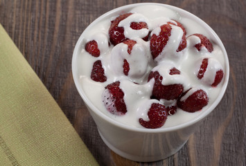 Strawberry with ice cream in a dish on a wooden table