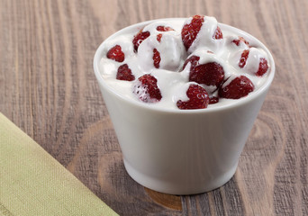 Strawberry with ice cream in a dish on a wooden table