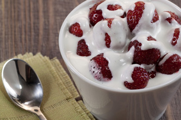 Strawberry with ice cream in a dish on a wooden table