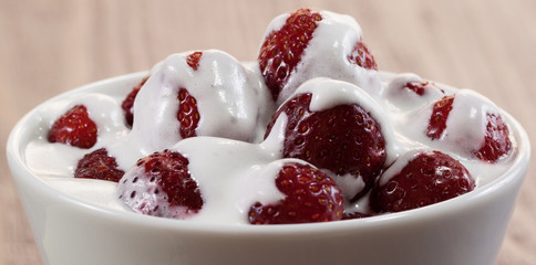 Strawberry with ice cream in a dish on a wooden table