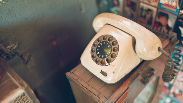 Antique telephone on a wooden glass cabinet in vintage style picture.
