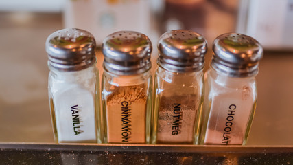A vanilla powder, cinnamon powder, nutmeg powder and chocolate powder in glass bottle in vintage style picture.