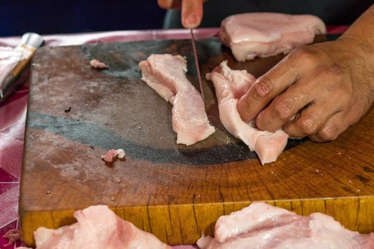 Butcher Hands Cutting Piece Of fresh Belly pork meat.
Raw pork on wooden cutting board.