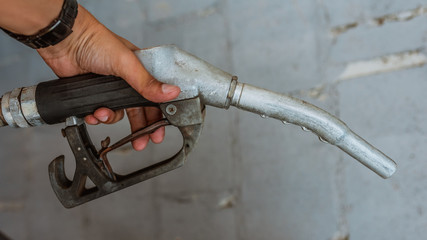 Man's hand holding a fuel steel metal nozzle.