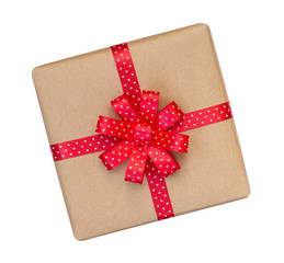 Gift box wrapped in brown recycled paper with red polka dot ribbon bow top view isolated on white background, clipping path included