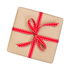 Gift box wrapped in brown recycled paper with red ribbon bow top view isolated on white background, clipping path included