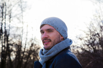 Handsome young man is traveling. He is looking forward in the forest at the nature. Blured background. He is froze.