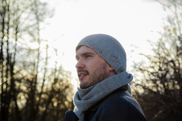 Handsome young man is traveling. He is looking forward in the forest at the nature. Blured background. He is froze.