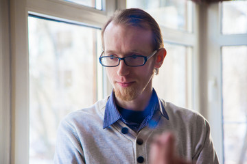 Thin man with a red beard waiting for someone at the window