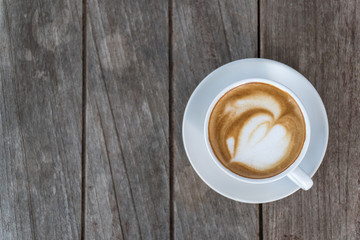 Hot coffee on wood table,Hot latte with heart sign on top of a cup.
