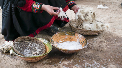 A Quechuan woman demsontrates alpaca wool weaving.