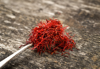 Saffron spice in spoon on wooden background