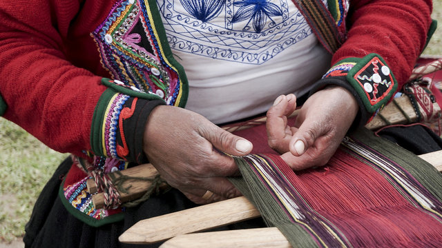A Quechuan woman demsontrates alpaca wool weaving.