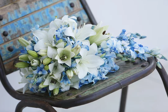 Bouquet da sposa con fiori azzurri, verdi e bianchi appoggiato su una  vecchia sedia Stock Photo