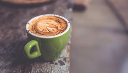 Latte art hot coffee in green cup in vintage style picture.