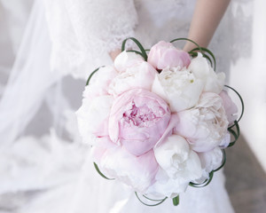 Sposa tiene in mano un delicato bouquet da matrimonio