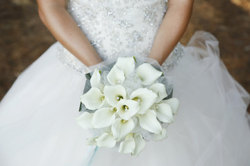 Sposa tiene in mano bouquet da matrimonio fatto di orchidee