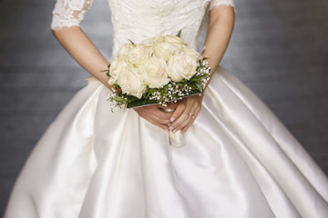 Sposa  vestita di bianco tiene in mano bouquet da matrimonio