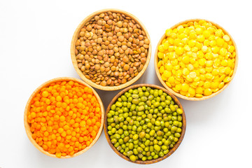 Four varieties of lentils in wooden bowls.