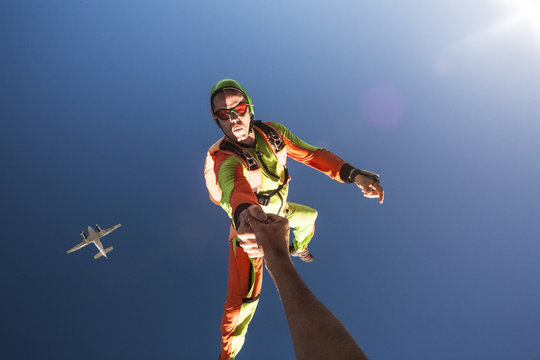 Skydiver holding someone's hand in air