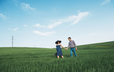 Naklejka na ściany i meble Happy family hugging in a field of green wheat