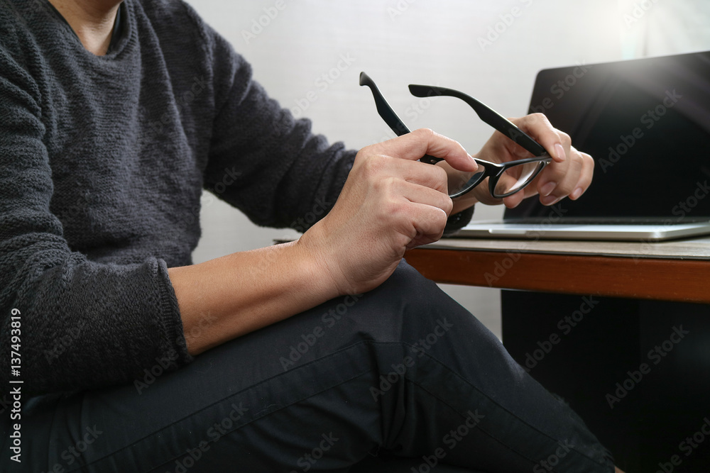 Aufkleber website designer holding eyeglass working computer laptop on wood table