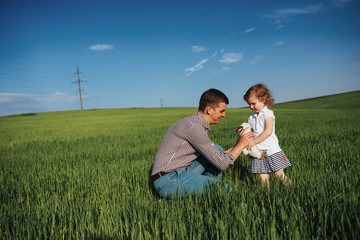 Fototapeta premium Happy father and baby rabbit on hands in field