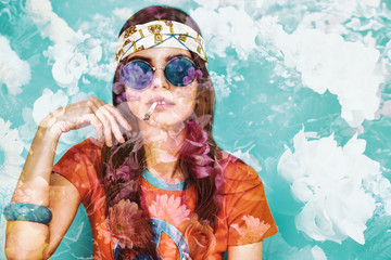 Double exposure of beautiful hippy girl smoking weed and flowers