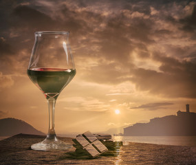Double exposure of wine glass with chocolate and sunset cloudscape