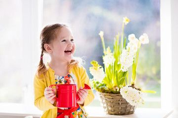 Obraz na płótnie Canvas Little girl watering spring flowers