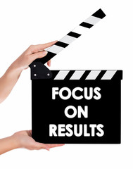 Hands holding a clapper board with FOCUS ON RESULTS text