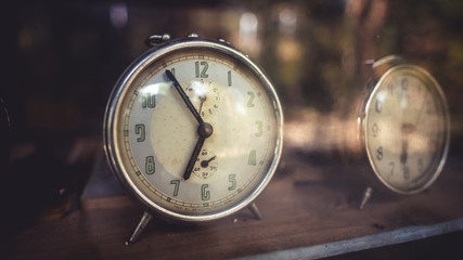 Retro alarm clock in a clear glass display cabinet in vintage style picture.