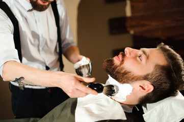 Master cuts hair and beard of men in the barbershop