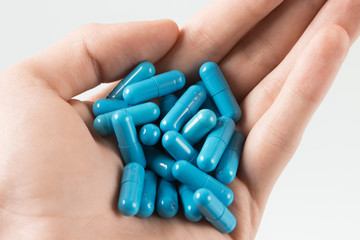man holding handful of pills. suicide by blue capsule